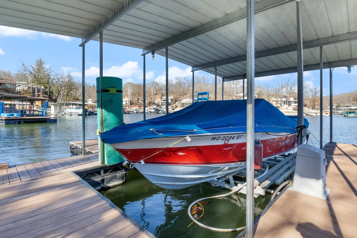A lively lakefront scene featuring a private dock with a boat tied up, calm water stretching into the distance, and lush trees creating a peaceful, natural setting. The dock is the focal point, perfect for fishing, launching kayaks, or gathering for picnics and family activities by the water.
